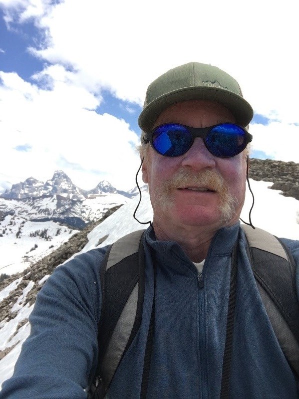 A selfie of Dan Bowler at the top of the Targhee Ski Resort with a view of Grand Teton in the background.