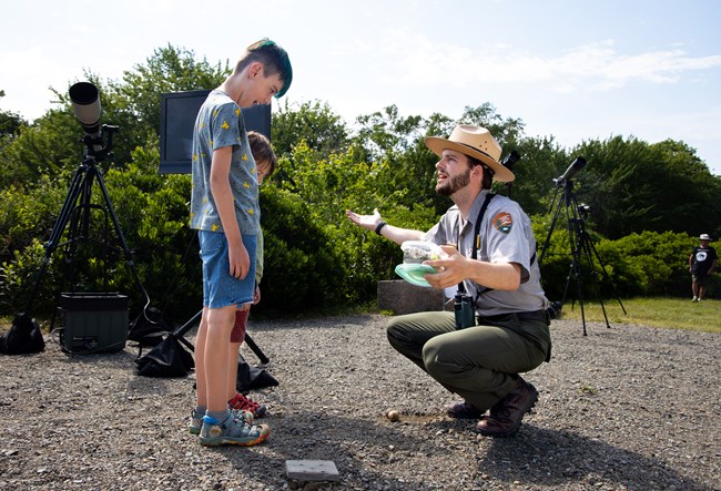 danielpefa two excited young visitors look on in excitement as a park ranger crouches to speak with them.