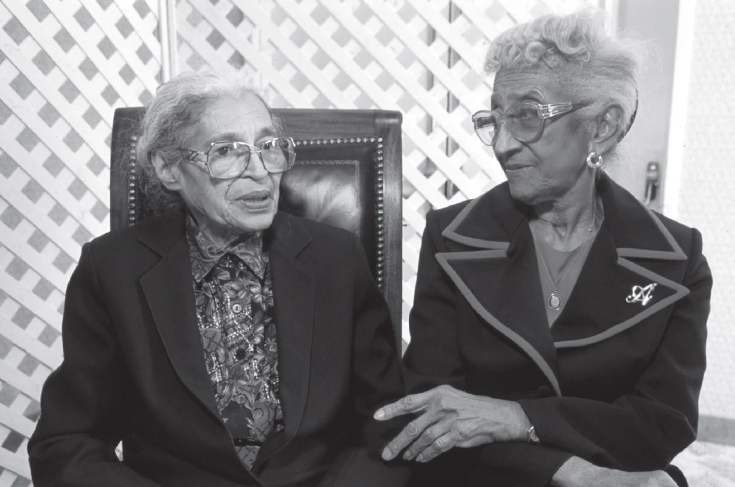 in a historic scene, two Black women sit and talk with one another.