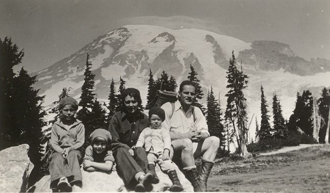 Man and women and three kids pose on a rock