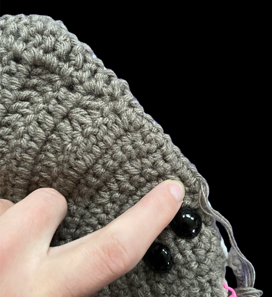 lt= Close up of crocheted halibut fin with a finger pointing to the end of the fin near the eyes.