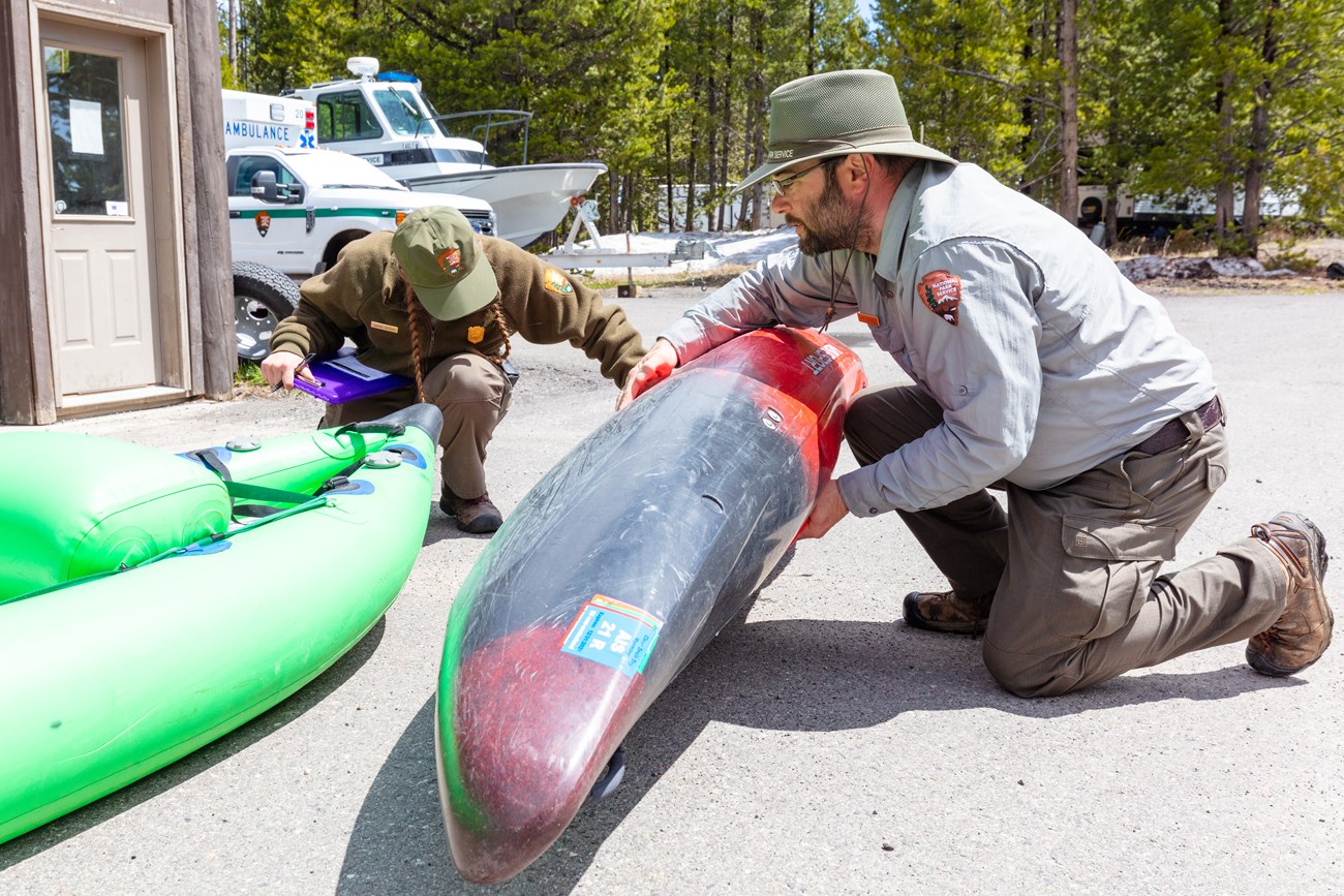 two people inspect kayaks in a parking lot