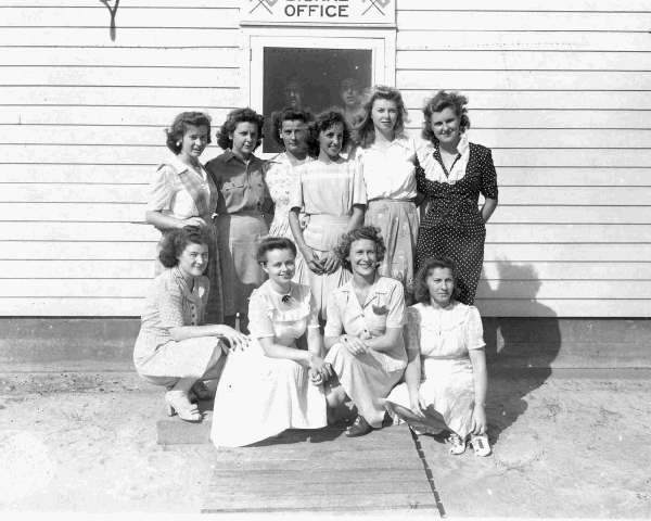 10 women employees of Camp Davis telegraph office. They are pictured in front of the telegraph office with 6 women standing and 4 women sitting down.