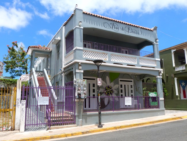 Gray building with purple fence and painted text