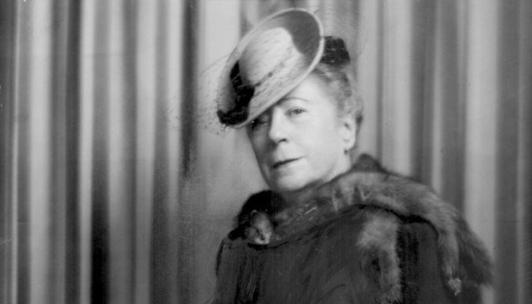 woman wearing a dress, hat, and a fur