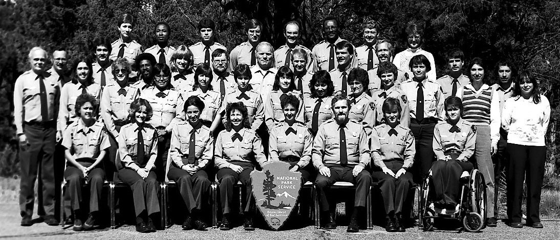 NPS ranger skills class, fall 1985 NPS employees pose for a group photo. Most wear NPS uniforms but a few are in street clothes. Erin Broadbent is in her wheelchair in the front row.