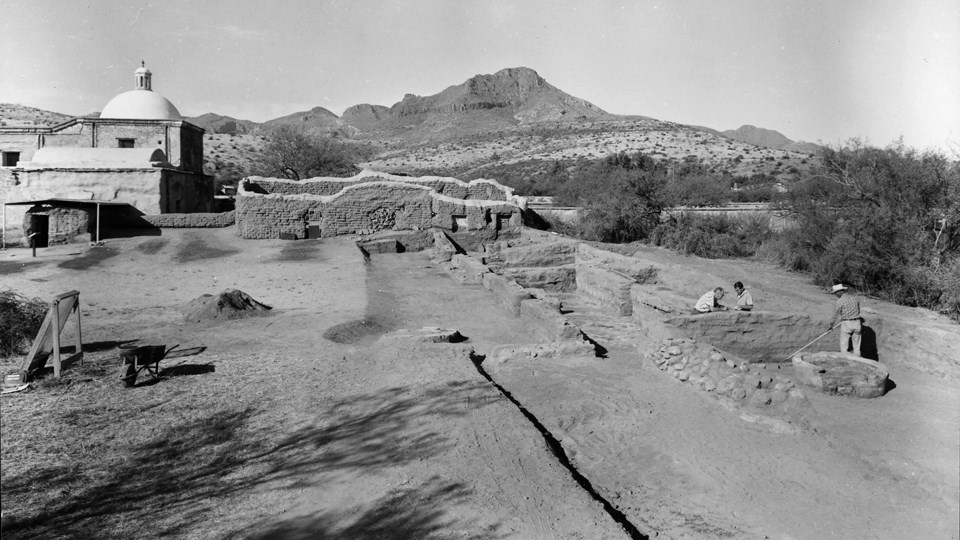 historic photo of excavated rooms extending from standing ruin site