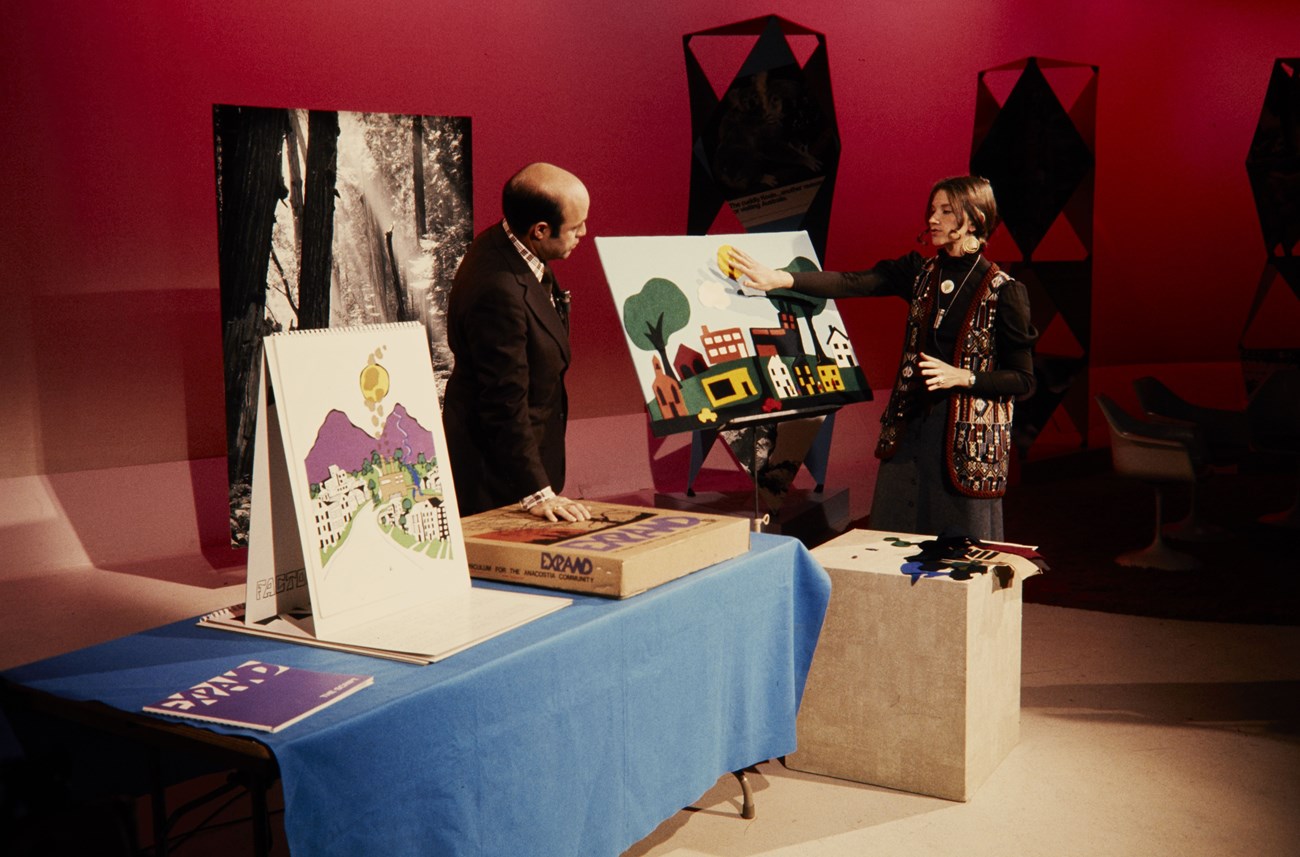 Woman showing a man posters on a TV set