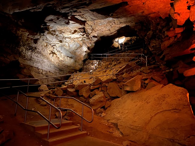 A hill in a cave with steep dirt trails winding up it.