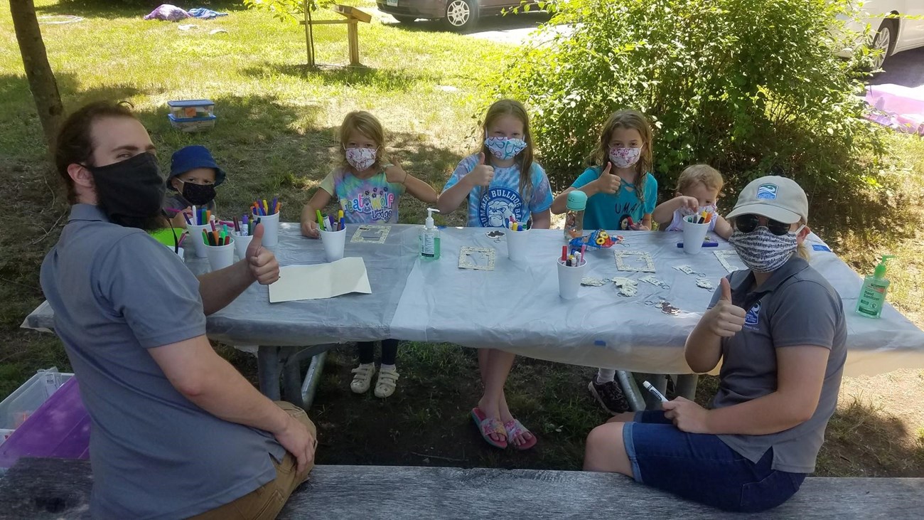 Participants from Family Fun Day sit at a picnic table and work on their crafting projects.