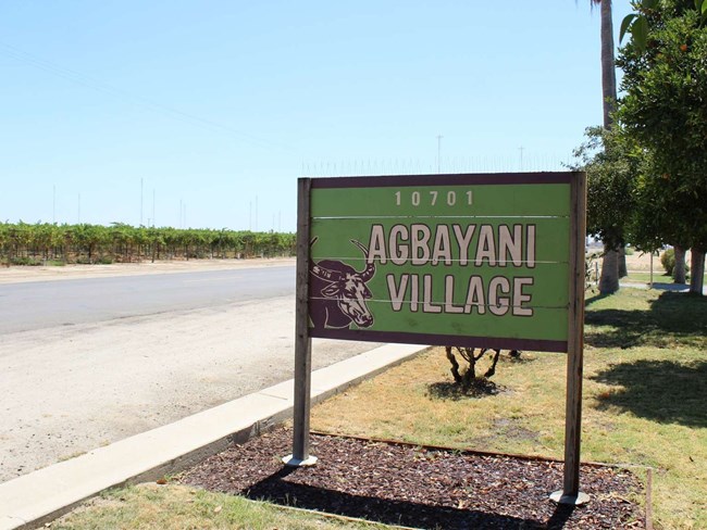 A sign saying Agbayani Village with a drawing of a water buffalo.