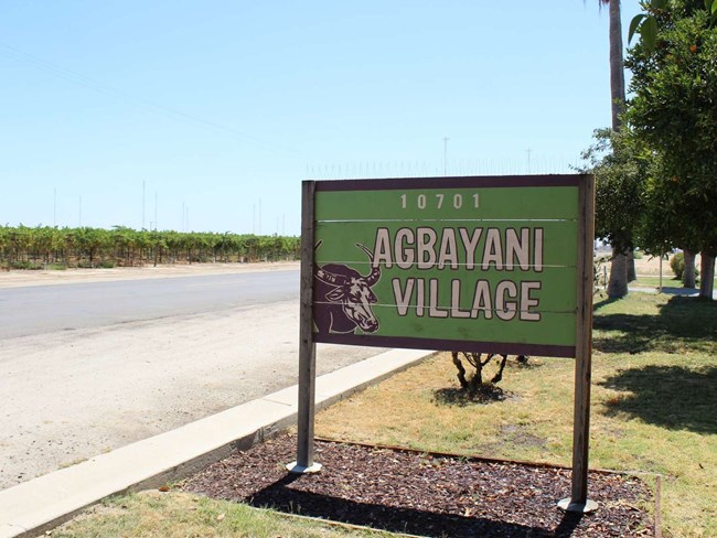 The entrance sign to Agbayani Village A sign saying Agbayani Village with a drawing of a water buffalo.