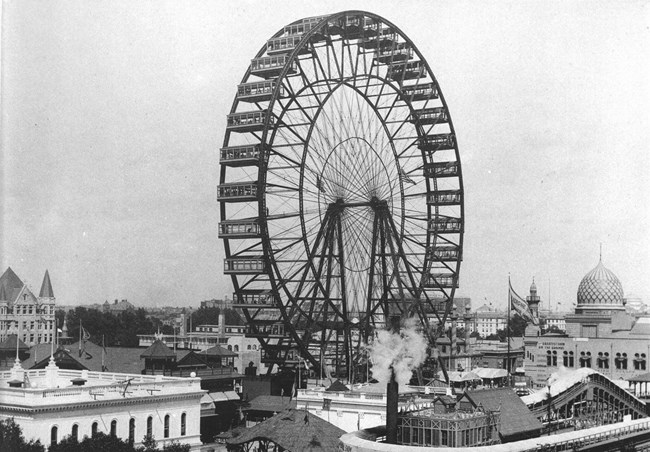Black and white of Ferris wheel rising above city of Chicago.