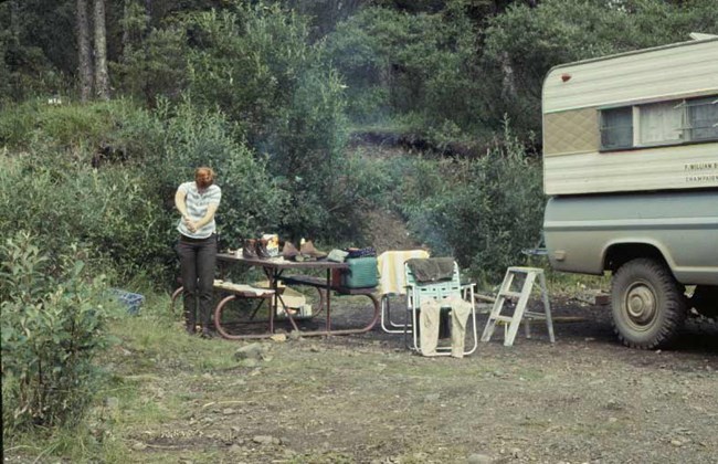 fig-6 a woman standing near a picnic table and car in a forest