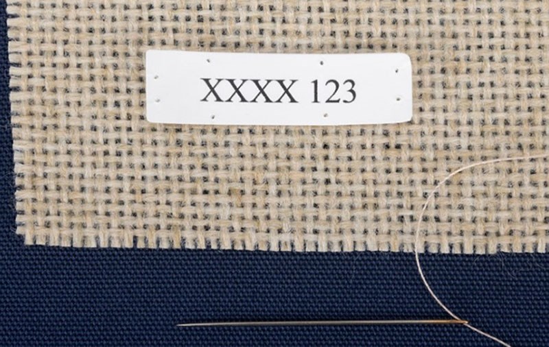 Label with pre-punched holes and appropriately sized needle for the textile.