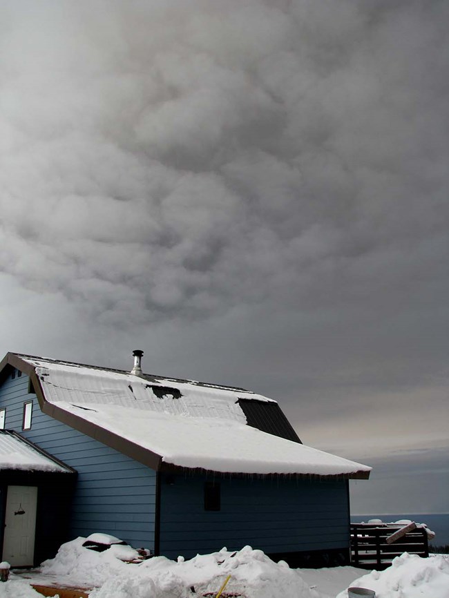 photo of a building with a large ash cloud above
