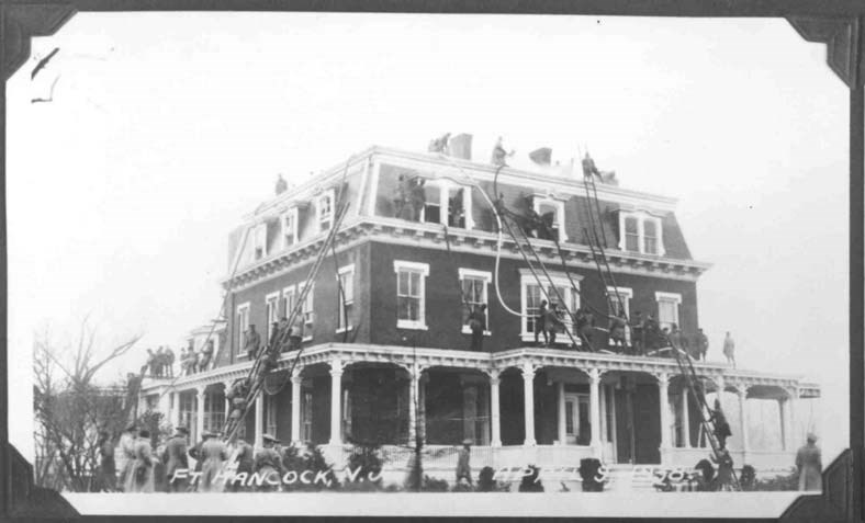firemen on ladders climb up the side of an ornate three-story building