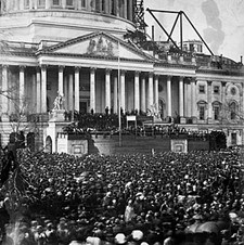 lt= A large crowd stands in front of the Capital Building. Abraham Lincoln is being sworn in.
