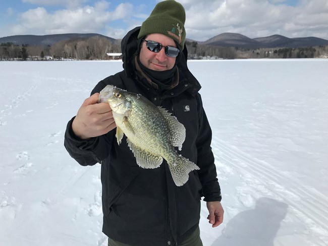 Henry holding a fish. A man holding a fish on a frozen lake