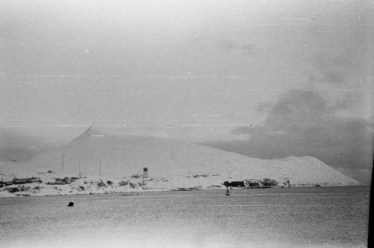 Water, snow-covered mountains, and some buildings in distance