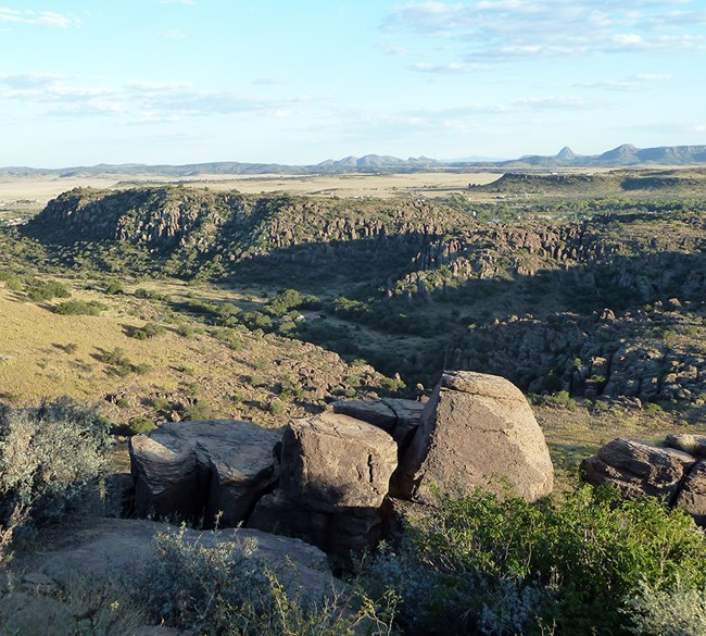 Fort Davis National Historic Site View of rocky desert hills covered in shrubs and valleys with desert plants and buildings.
