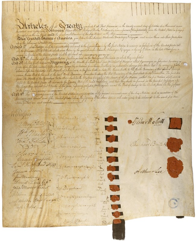 An old parchment paper with cursive handwriting, red wax seals, and signatures crowded on it.