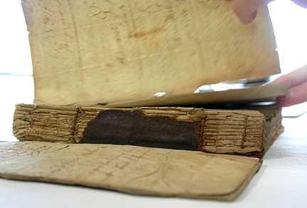 The leather on the old book's spine is nearly gone. You can see the worn binding underneath.