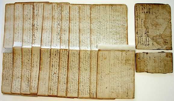 On a table, different sections of the old book are laid out in separate stacks.