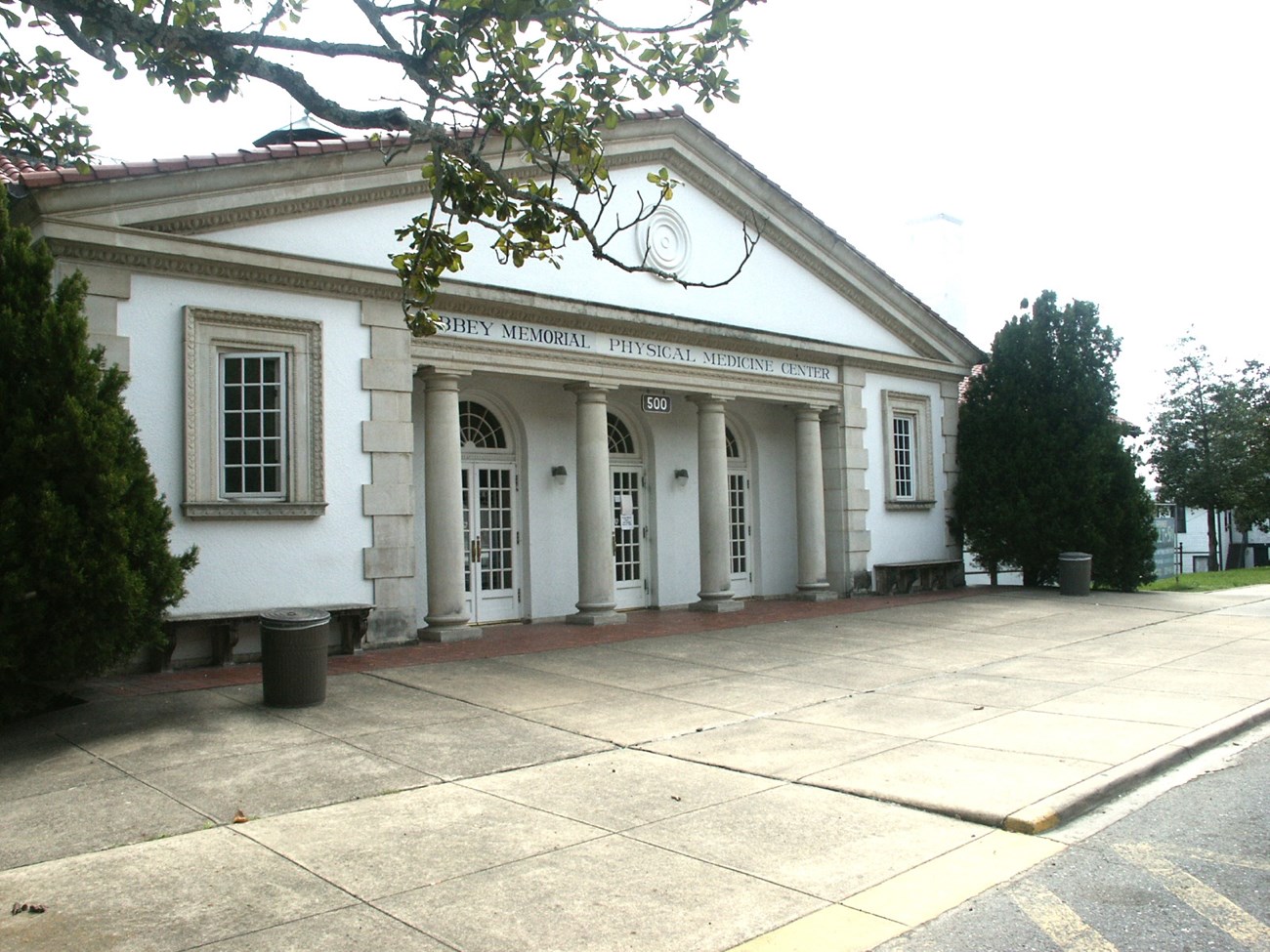 A triangular building with many columns out front stands tall in the daylight.