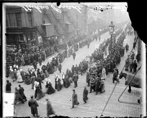 Overhead view of people marching in a city street. Black and white photo.