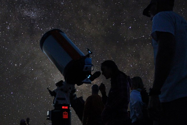 A person looks through a telescope under a starry sky A person looks through a telescope under a starry sky