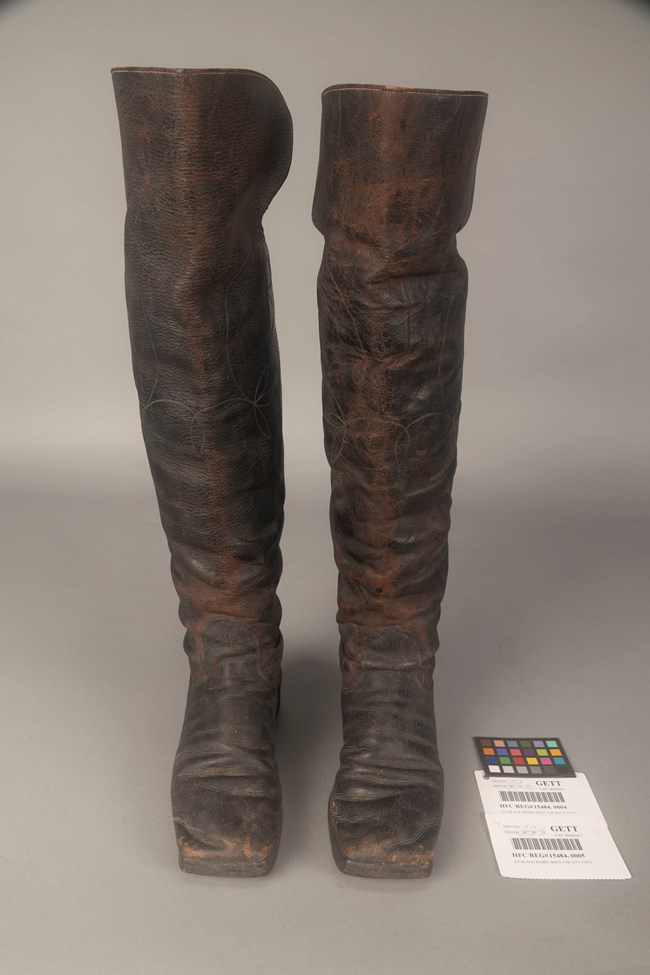 A pair of dark brown boots on a tan surface.