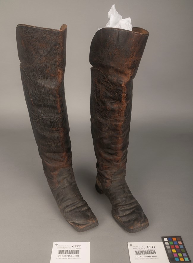 A pair of dark brown boots on a tan surface.