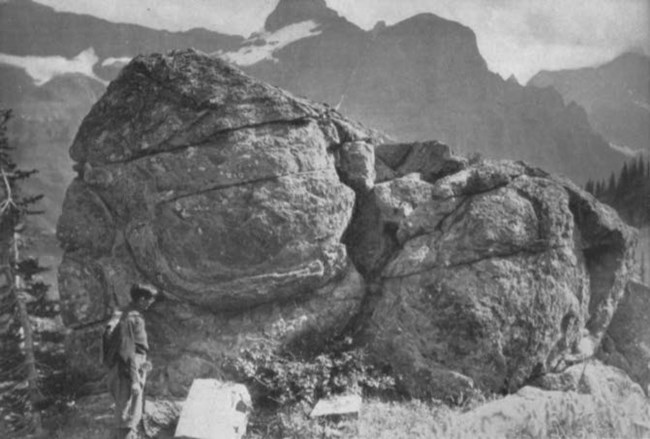 a person standing next to a large rock outcrop