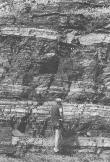 a person standing at the base of a banded cliff