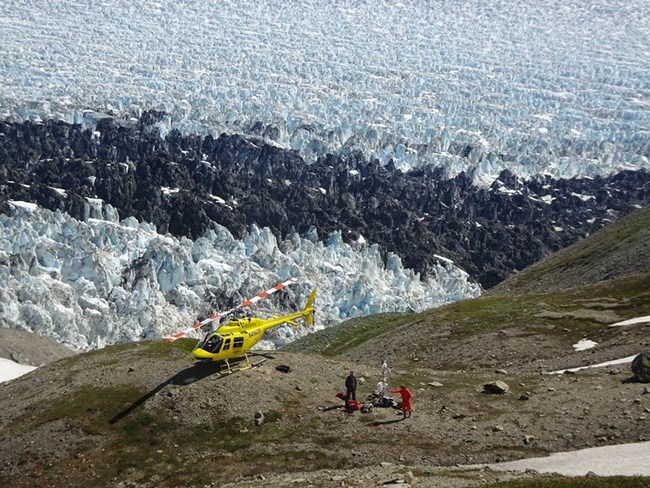 a helicopter landed by a glacier