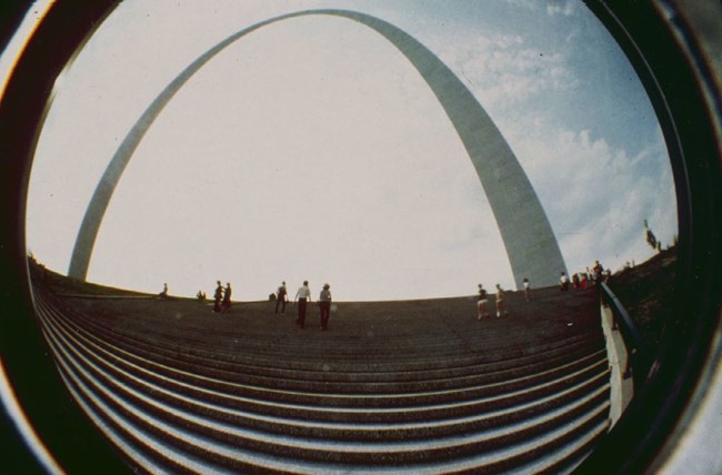 A fisheye view of concrete steps with the gateway arch behind it.