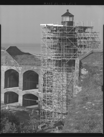 Black and white HABS photograph showing several levels of metal scaffolding surrounding a historic lighthouse.