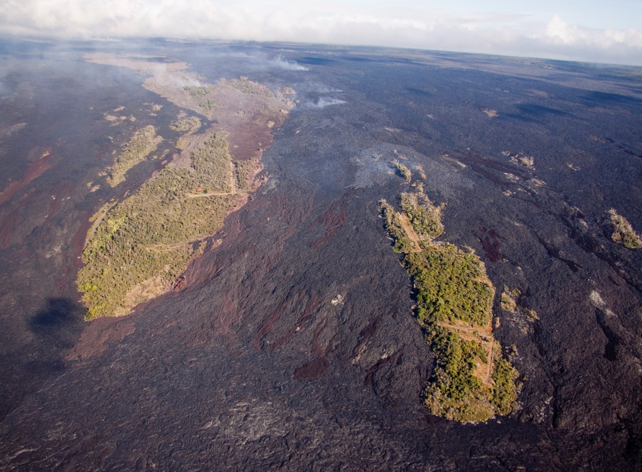 photo of a volcanic landscape with recent lava flows surrounding vegetated areas of older flows