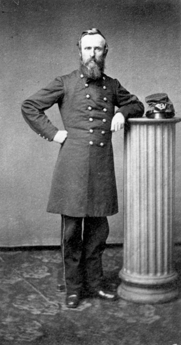 man wearing a Union blue Ciivl War uniform leaning against a pillar while hat rests on pillar