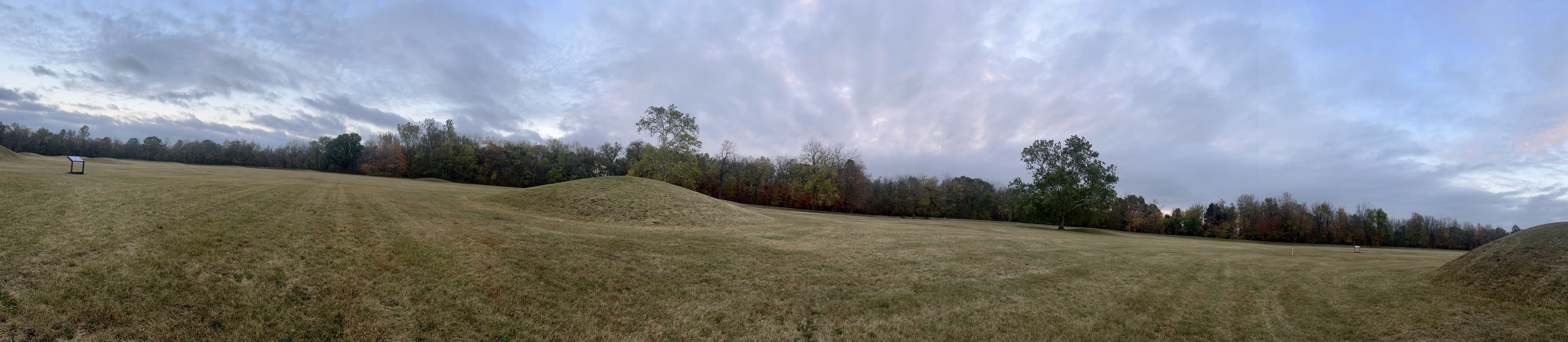 Mound City Group at Hopewell Culture National Historical Park. Earthen mounds in a large grassy area surrounded by trees with autumn leaves.