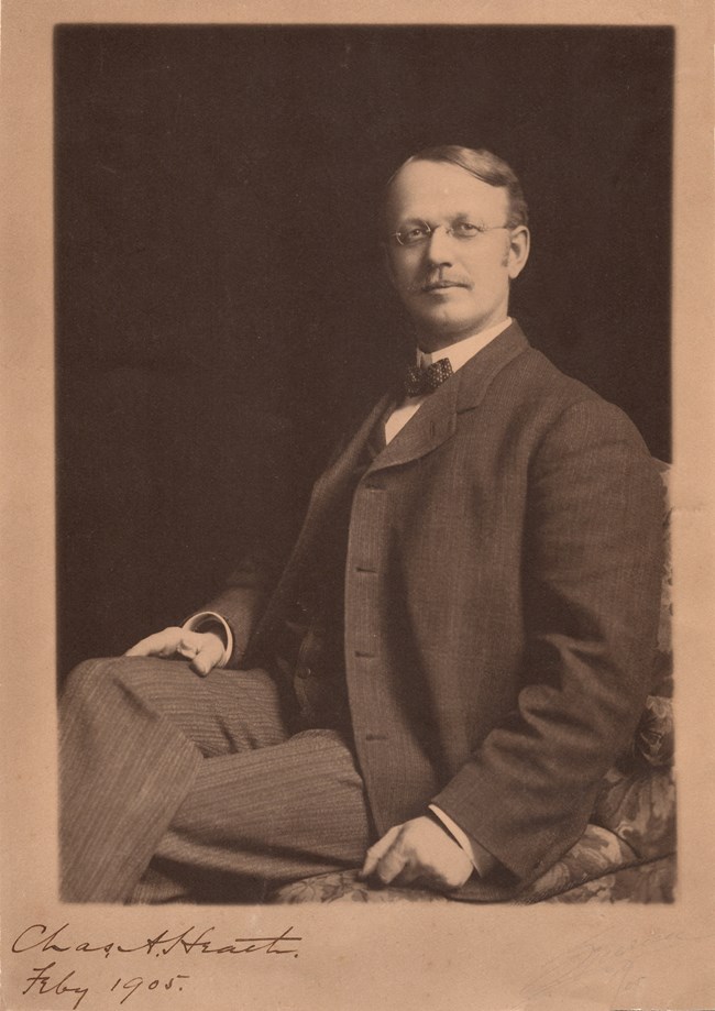 Portrait of a man in a suit with mustache and glasses
