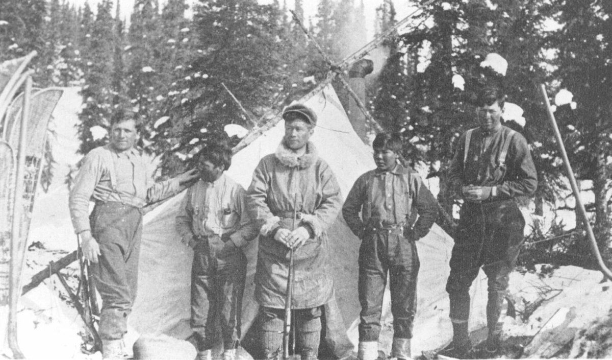 five men standing outside a tent in a snowy forest
