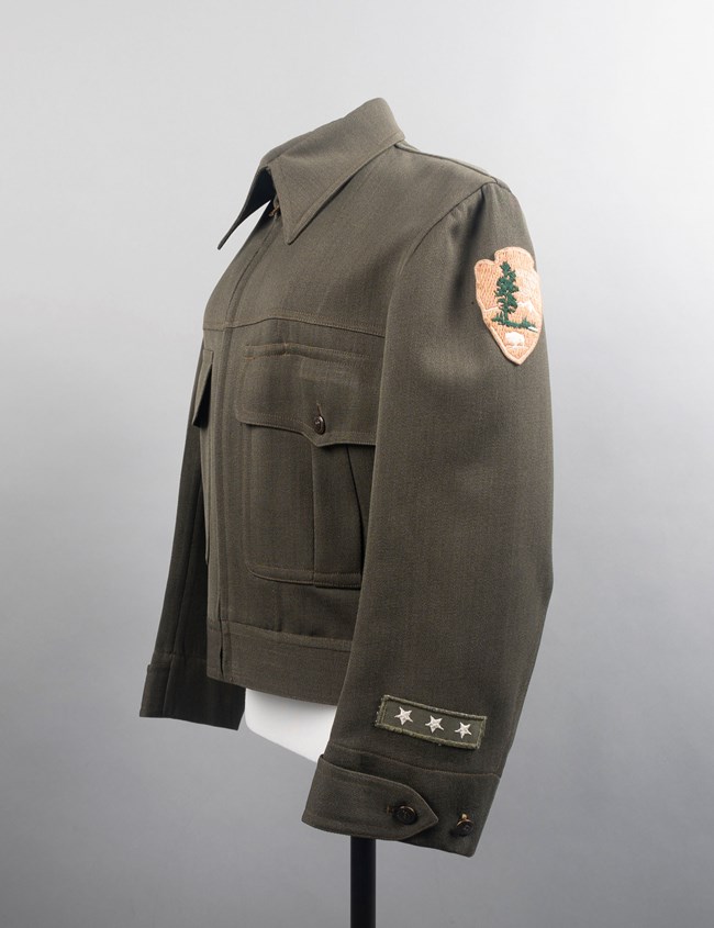 Green uniform coat with arrowhead patch and three stars on sleeve