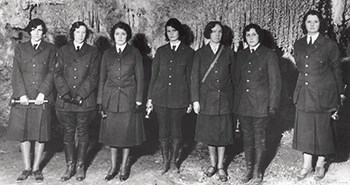 Seven women wearing NPS uniforms stand in a cavern facing the camera.