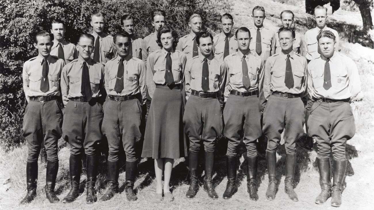 Two rows of uniformed rangers stand shoulder to shoulder.  The front center is a woman wearing a skirt while all the men wear breeches.