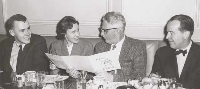 Historic structures dinner Three men and a woman sit at a table looking at a brochure
