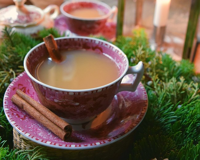 Hot buttered rum in a teacup with a cinnamon stick.