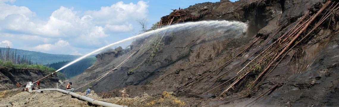 A large jet of water spraying an exposed cliff to erode minerals.