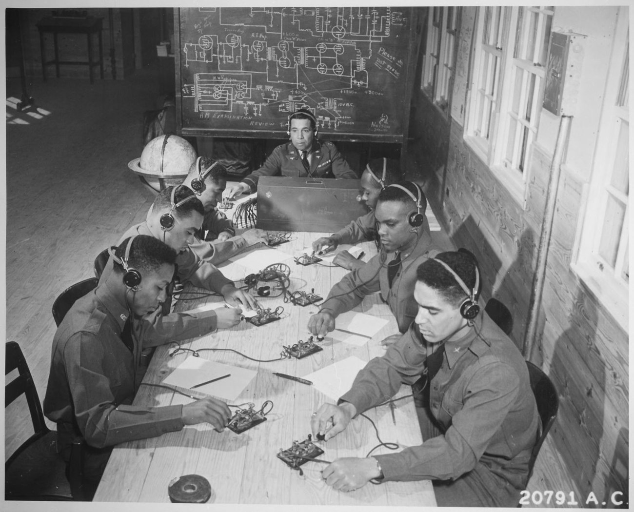 Cadets being taught to send and receive code. There is a blackboard behind them with instructions.